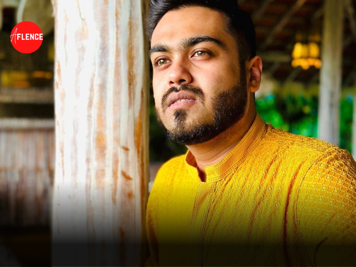 Portrait photo of 8bit Mamba wearing a yellow kurta, standing by a pillar and looking off-camera.