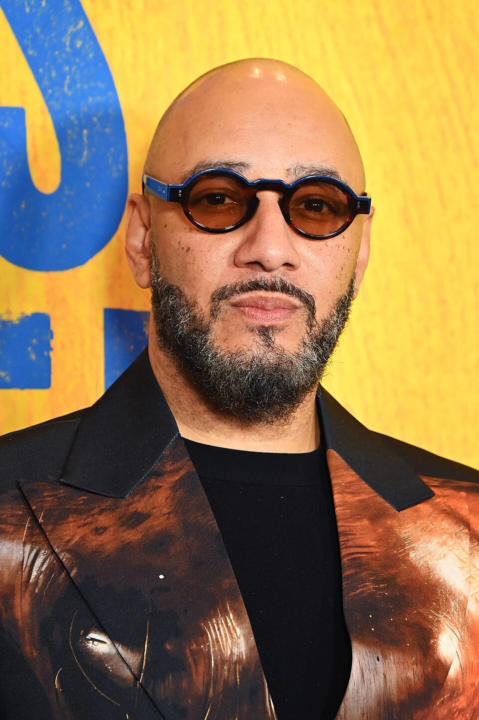 Swizz Beatz at an event, wearing sunglasses and a patterned jacket